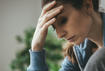 woman with head in hands looking down serious expression