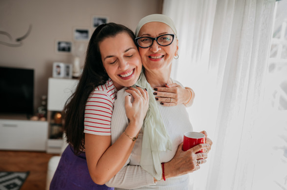 Cancer patient in treatment hugging her daughter